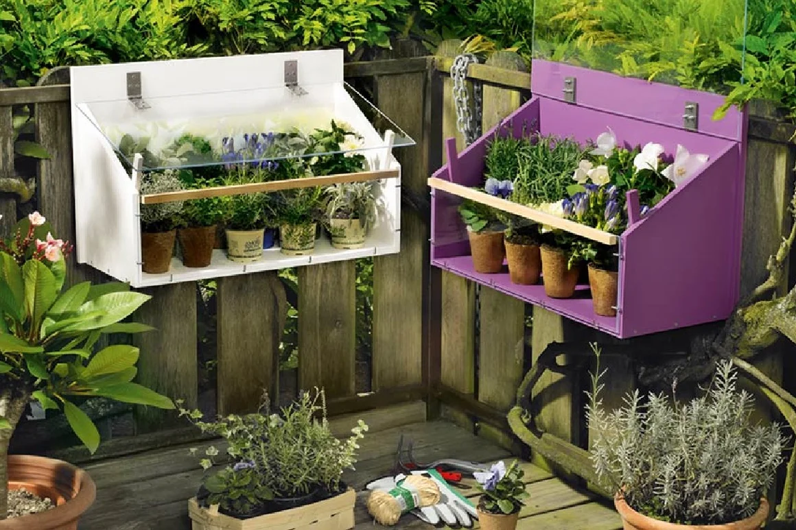 Zwei kleine Blumenkästen hängen an einem Gartenzaun.